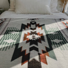 Load image into Gallery viewer, Close-up of a patterned blanket with geometric design on a bed.