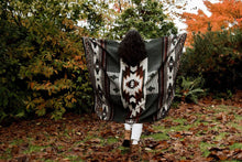 Load image into Gallery viewer, Person holding a patterned blanket in an autumnal setting with trees and fallen leaves.