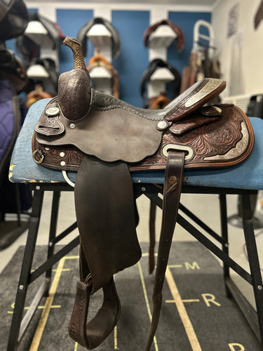 Brown leather saddle on a blue stool with a blurred background of horse equipment.