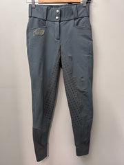 A pair of gray equestrian riding breeches hanging on a wooden hanger against a plain light gray wall. The pants feature a high waist with snap buttons, side pockets, textured grip panels on the lower legs, and a small embroidered logo on the left thigh.