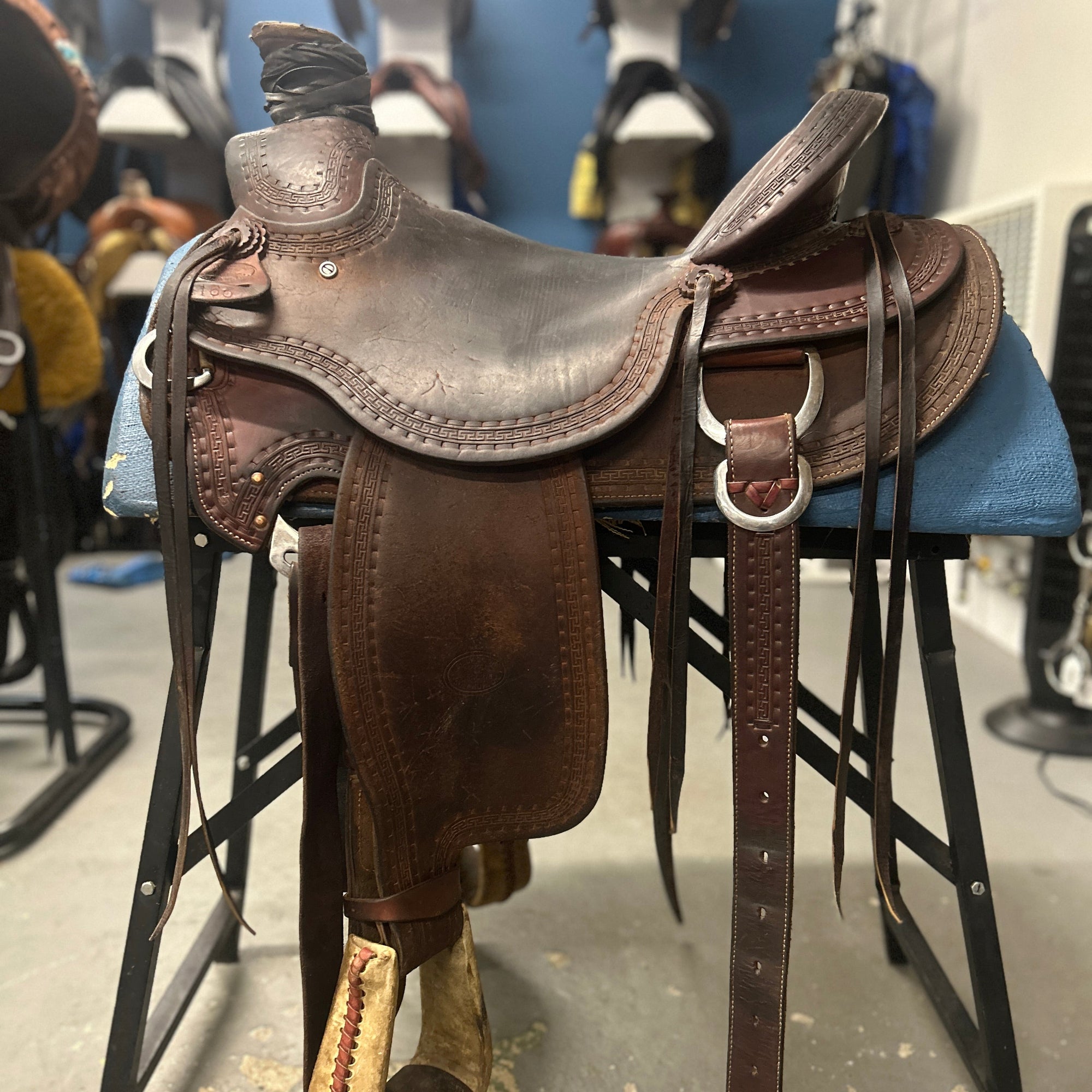 Brown leather saddle on a stand with a blue background