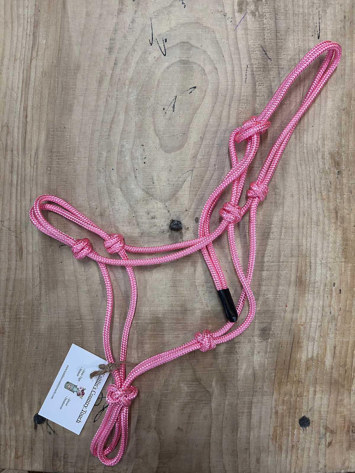 Soft Pink Pony Sized Rope Halter for Horses on a Light Wood Background 